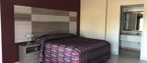 Un dormitorio con cama, mesita de noche, espejo y armario.