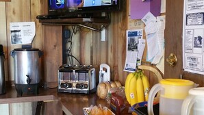 A rustic kitchen with a wooden interior, a television mounted on the wall, a coffee maker, a toaster, and various food items on the counter. - Ontario Inn (Ontario)