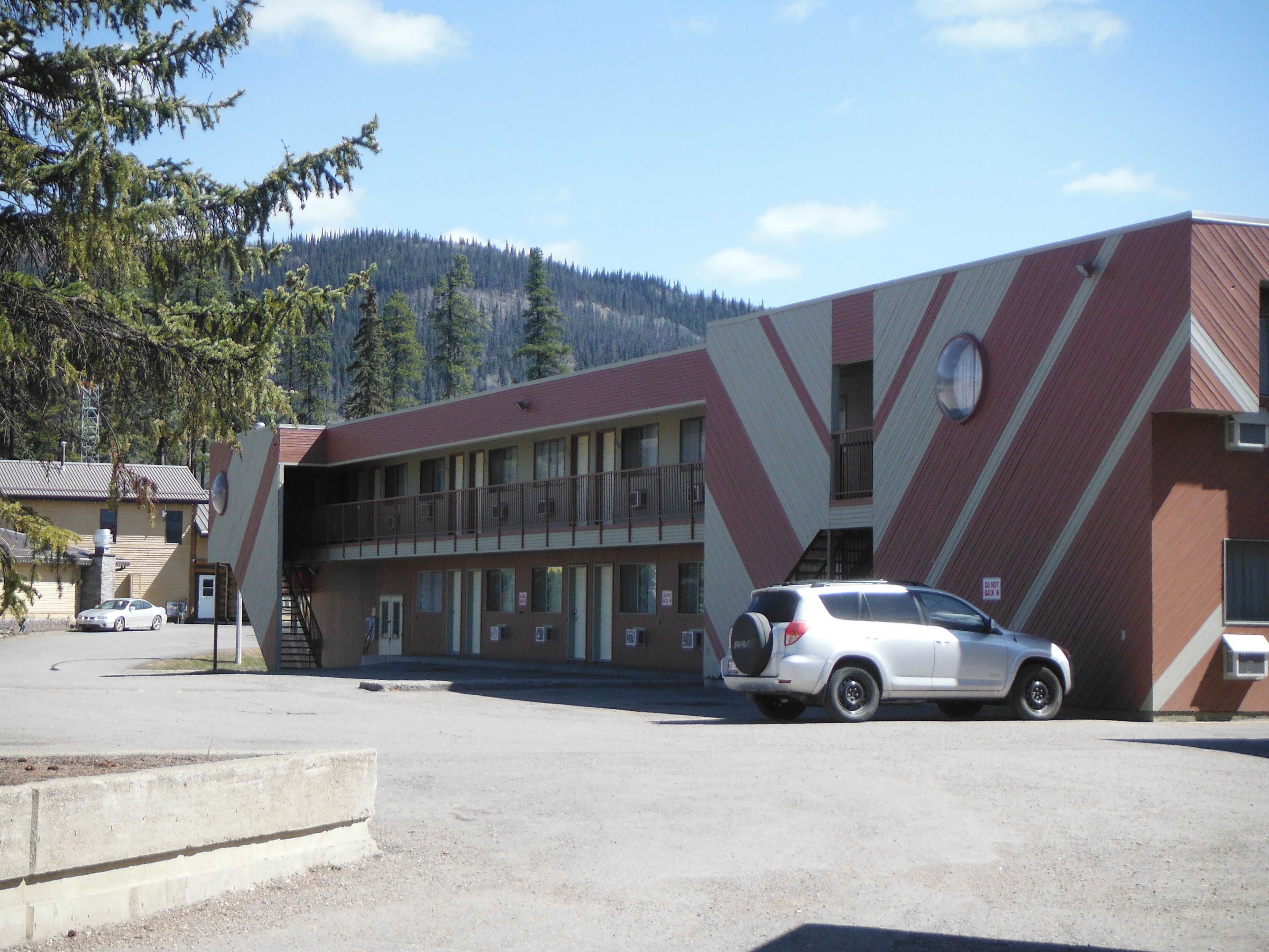 A building with a distinctive zigzag pattern on its facade, a parking lot, and a white SUV parked in front.