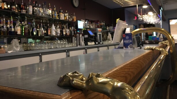 A bar area with shelves of liquor bottles, a clock on the wall, and a golden bar counter. - Tumbler Ridge Inn (Tumbler Ridge)