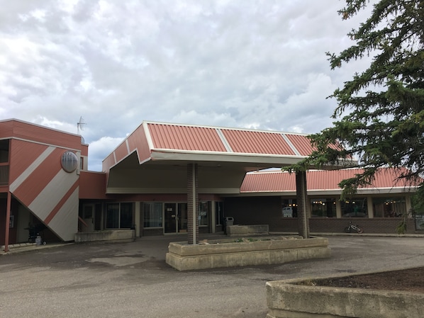 A building with a red and white striped facade, a covered entrance, and a brick column in the center.