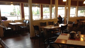 A restaurant with wooden tables and chairs, large windows, and a view of the outdoors. - Tumbler Ridge Inn (Tumbler Ridge)