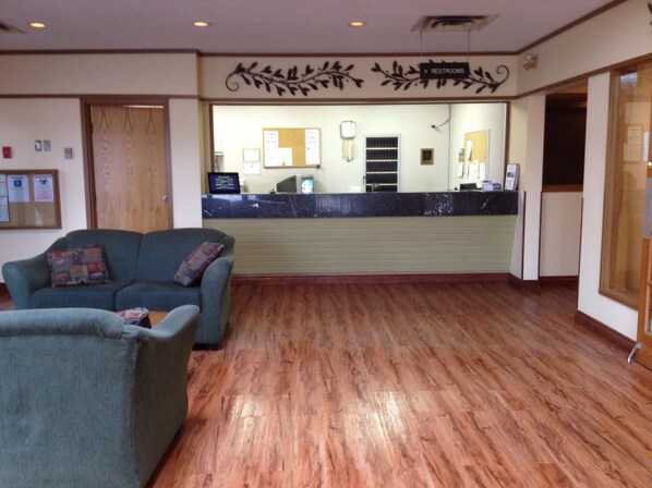 A reception area with a counter, a seating area with two sofas, and a wooden floor.