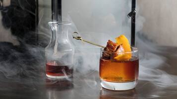 A glass of amber-colored liquid with a garnish and a hookah in the background.