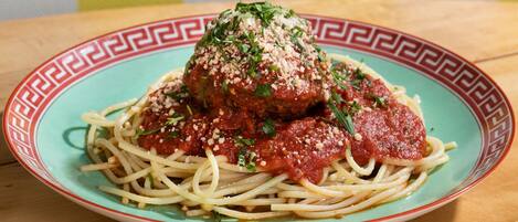 A plate of spaghetti with meatballs and tomato sauce, garnished with herbs and grated cheese.