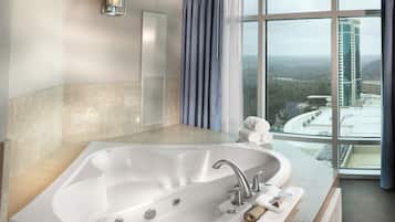 A modern bathroom with a large bathtub, a window with a view of a cityscape, and a towel on the counter.