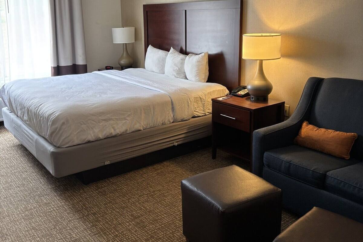 Une chambre d’hôtel avec un grand lit, un bureau, une chaise et une lampe.