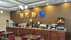 A hotel breakfast area with a buffet setup, including a coffee machine, fruit juice dispenser, and various food items. - Comfort Inn Naugatuck-Shelton, CT (Naugatuck)