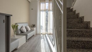 A modern living room with a grey sofa, a small table with a vase of flowers, and a staircase with granite steps. - Standbyme Ramblas (Barcelona)