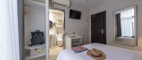 Habitación de hotel con cama, escritorio, armario y aire acondicionado.