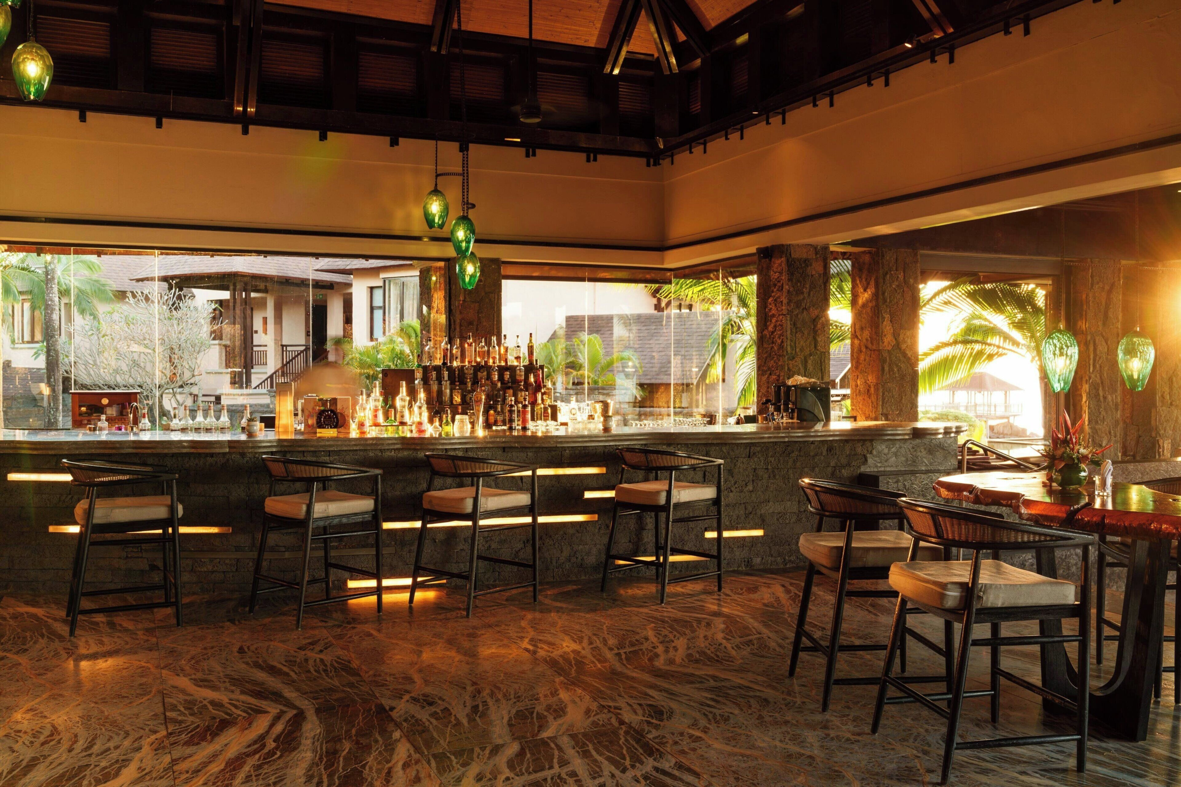 A bar area with a marble floor, multiple stools, and a bar counter with various bottles.