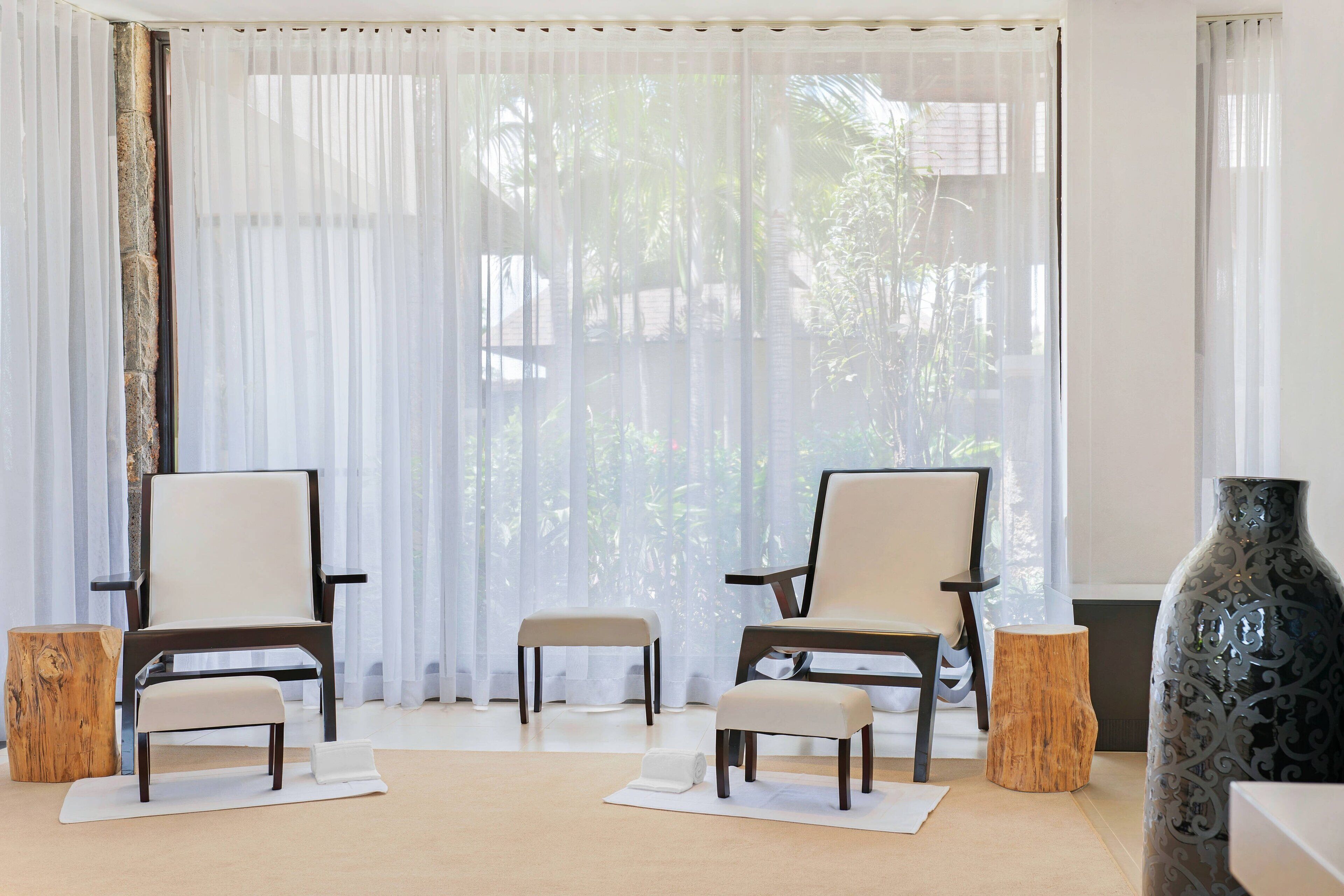 A modern living room with two armchairs, a small table, and a decorative vase.