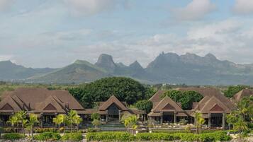 Un resort con varias construcciones tipo bungalow, una costa rocosa y montañas al fondo.