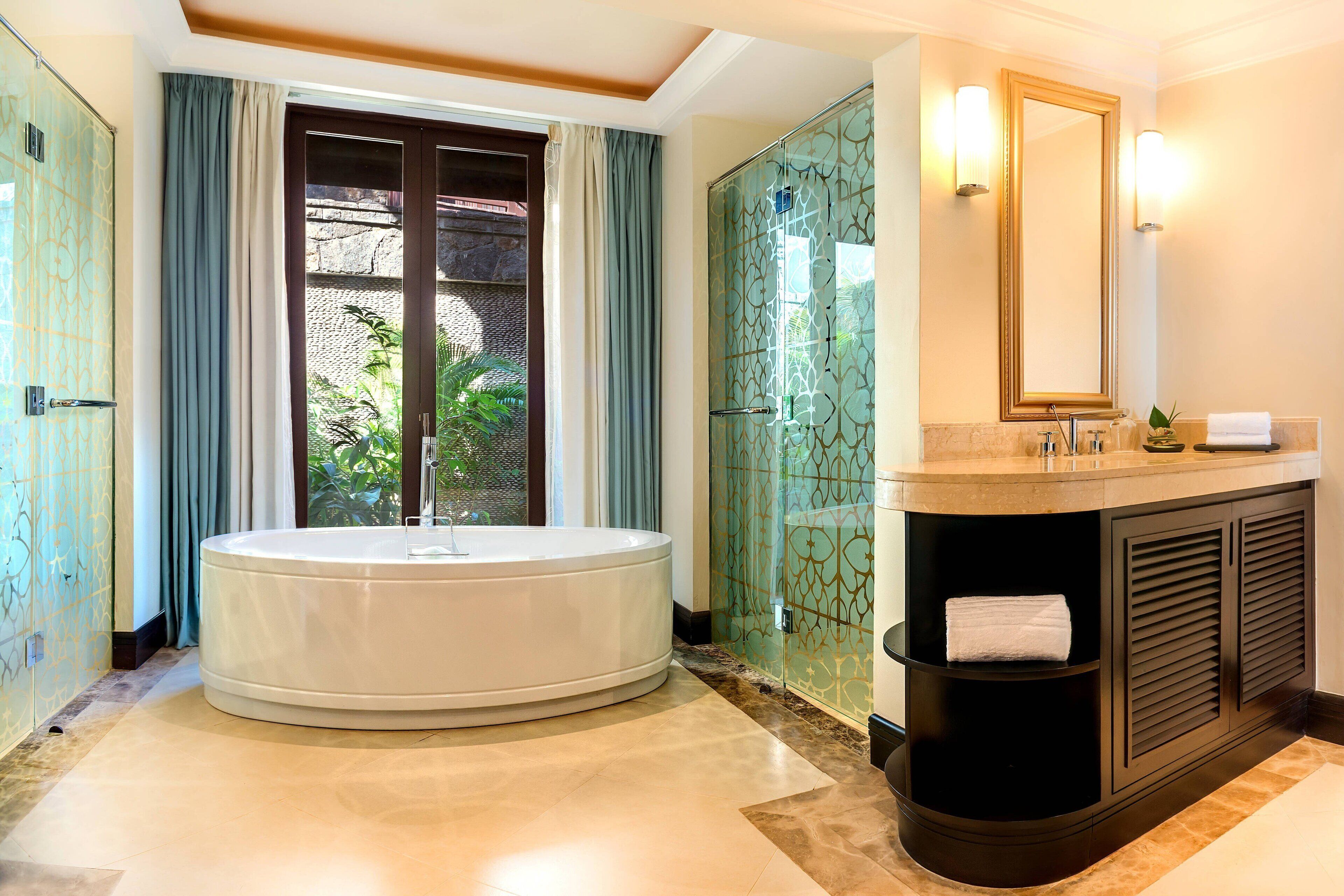 A bathroom with a large bathtub, a vanity with a mirror, and a shower enclosure.