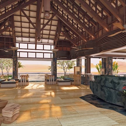 A spacious indoor area with wooden flooring, a large seating area with cushions, and a view of the beach.