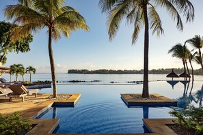 A poolside area with lounge chairs and palm trees, overlooking a calm body of water. - The Westin Turtle Bay Resort & Spa, Mauritius (Balaclava)