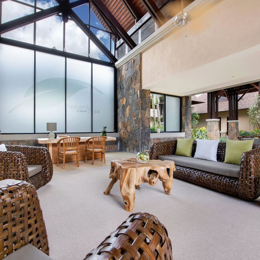 A spacious indoor area with wicker furniture, a stone wall, and a large window providing natural light.