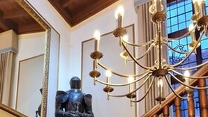A wooden staircase with a chandelier and a statue. - Farnham House Hotel (Farnham)