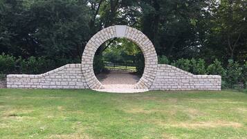 A stone archway in a park with a pathway leading through it.
