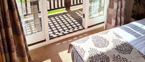 A bedroom with a bed, a window, and a sliding glass door leading to a balcony.