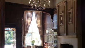 A spacious room with a large wooden floor, a fireplace, and a chandelier. - Farnham House Hotel (Farnham)