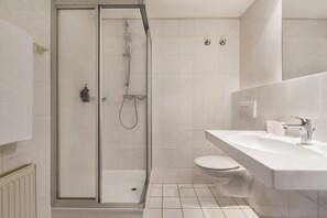 A modern bathroom with a glass-enclosed shower, a white sink, and a toilet. - Good Morning + Halle - Leipzig (Kabelsketal)