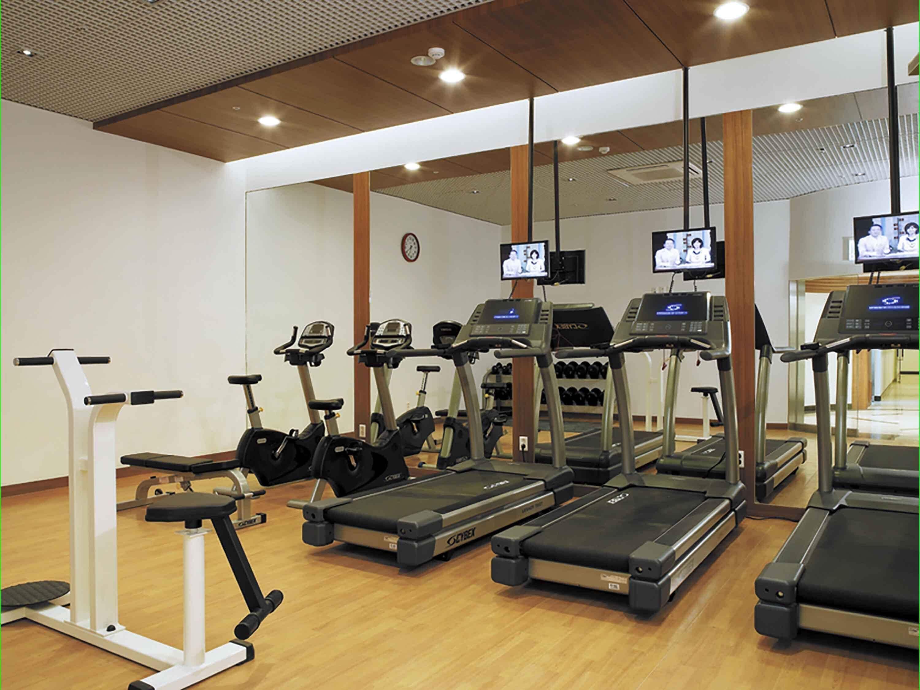 A gym with treadmills, elliptical machines, and weight benches.