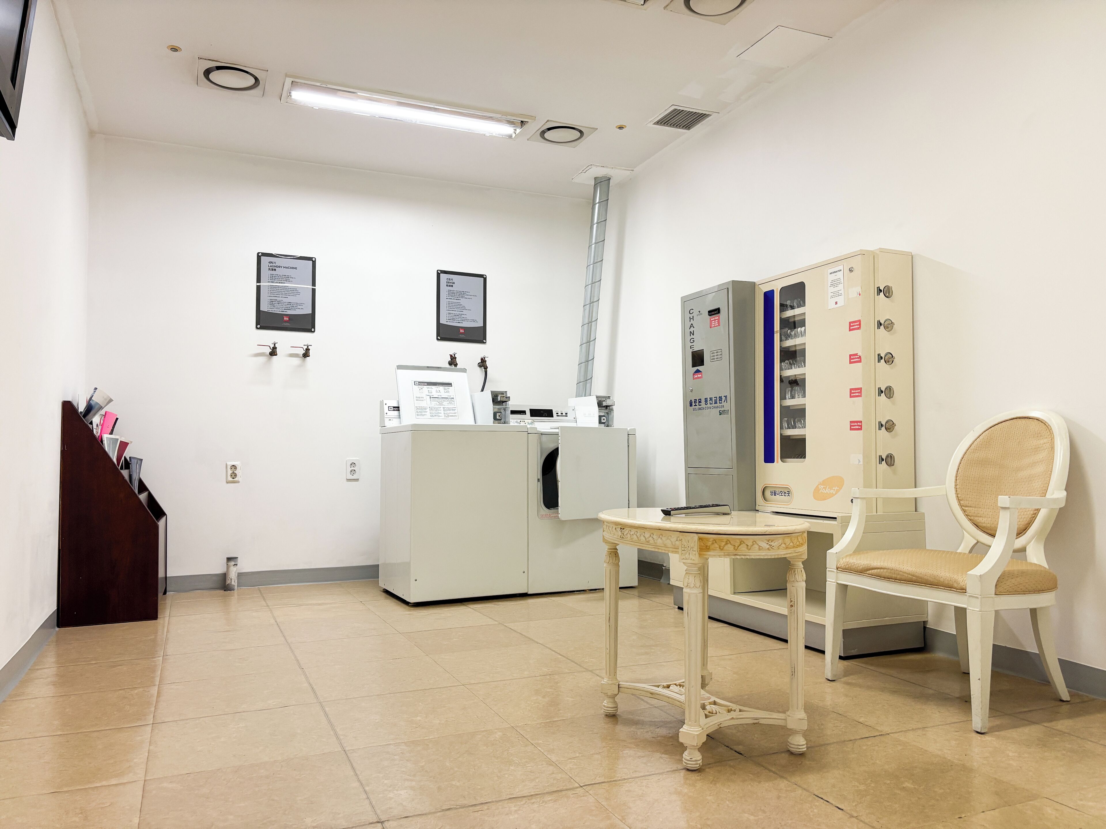 Un entorno clínico con un mostrador de recepción, carteles informativos, un gabinete de vidrio y una sala de espera con una silla.