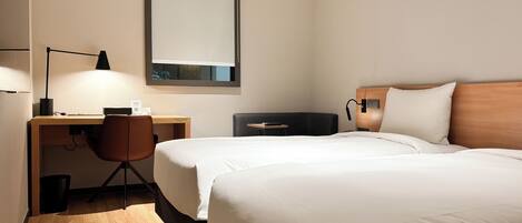 A hotel room with a bed, a desk, a chair, and a nightstand.