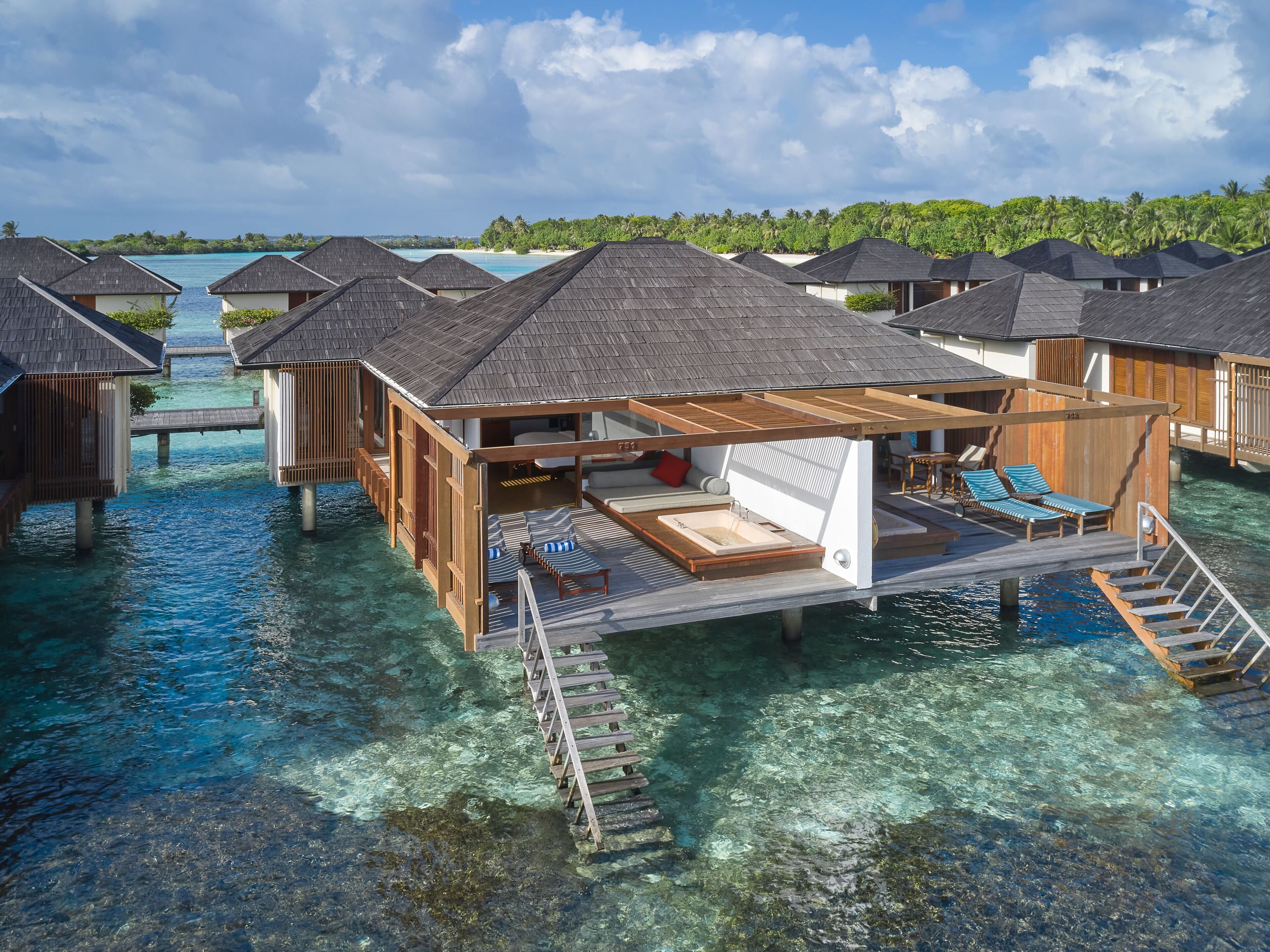 Overwater bungalows with wooden decks and a hot tub.