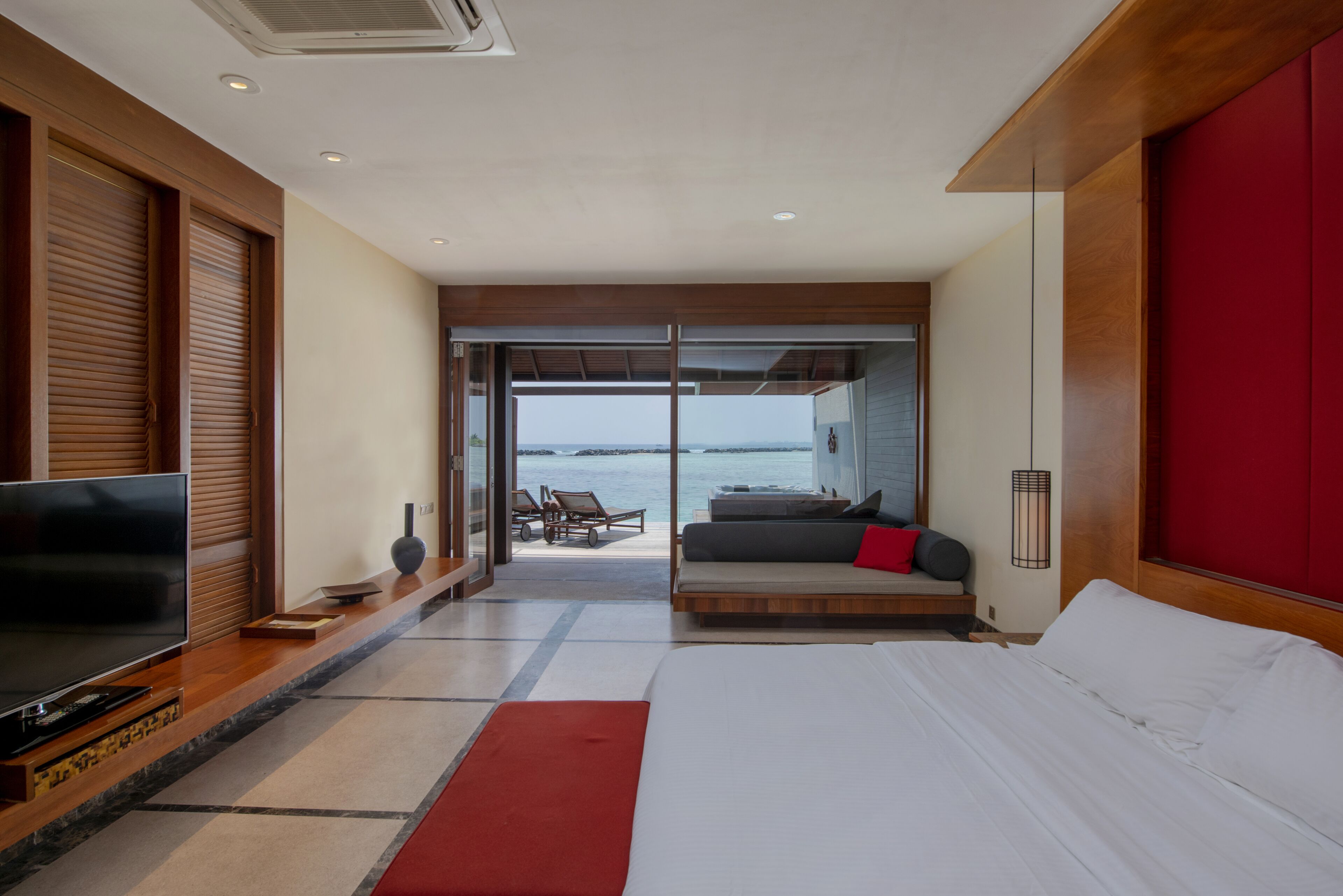 Une chambre d’hôtel moderne avec un grand lit, une télévision et une vue sur la mer.