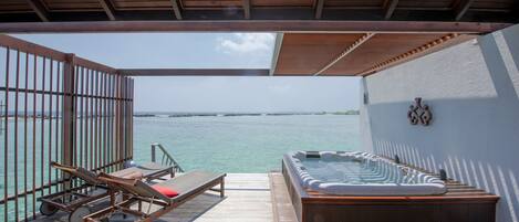 Terraza de madera con jacuzzi y sillones de descanso con vistas a un cuerpo de agua.