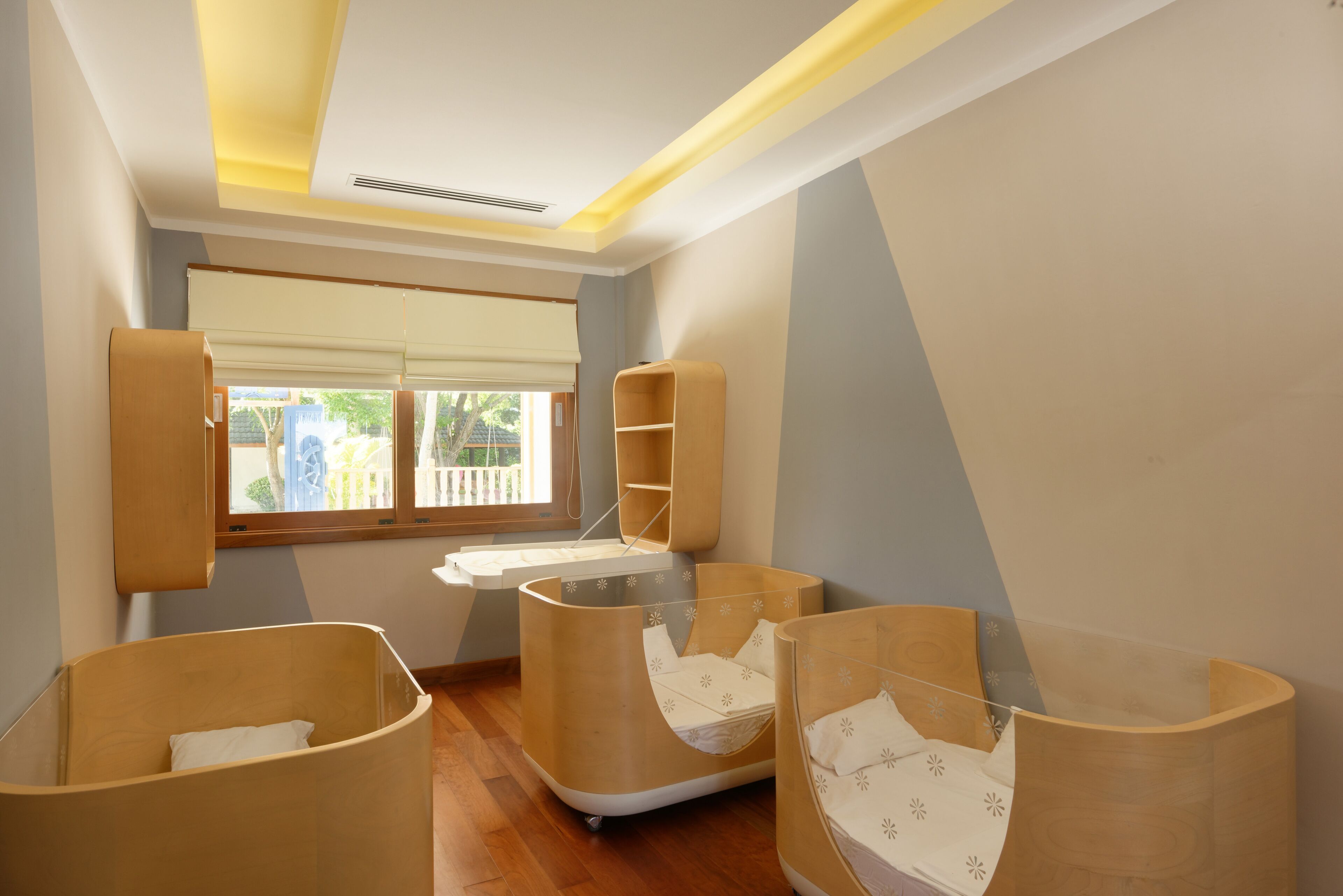 Una habitación con techo inclinado, una ventana con persianas, y tres literas de madera con ropa blanca de cama.