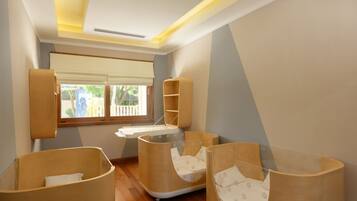 Una habitación con techo inclinado, una ventana con persianas, y tres literas de madera con ropa blanca de cama.