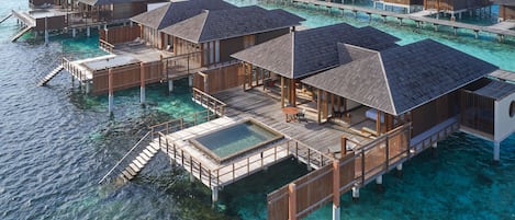 Des bungalows sur pilotis dotés de terrasses en bois et de piscines à débordement, reliés par des passerelles.
