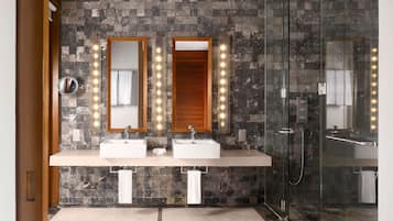Een moderne badkamer met twee wastafels, een douchecabine van glas en een spiegel met verlichting.