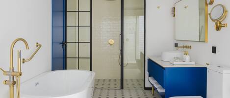 Ein modernes Badezimmer mit einer freistehenden Badewanne, einer begehbaren Dusche und einem Waschtisch mit Spiegel.