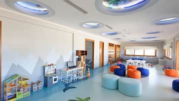 A children's playroom with a mountain mural, a turtle decal, and a ceiling with circular skylights.
