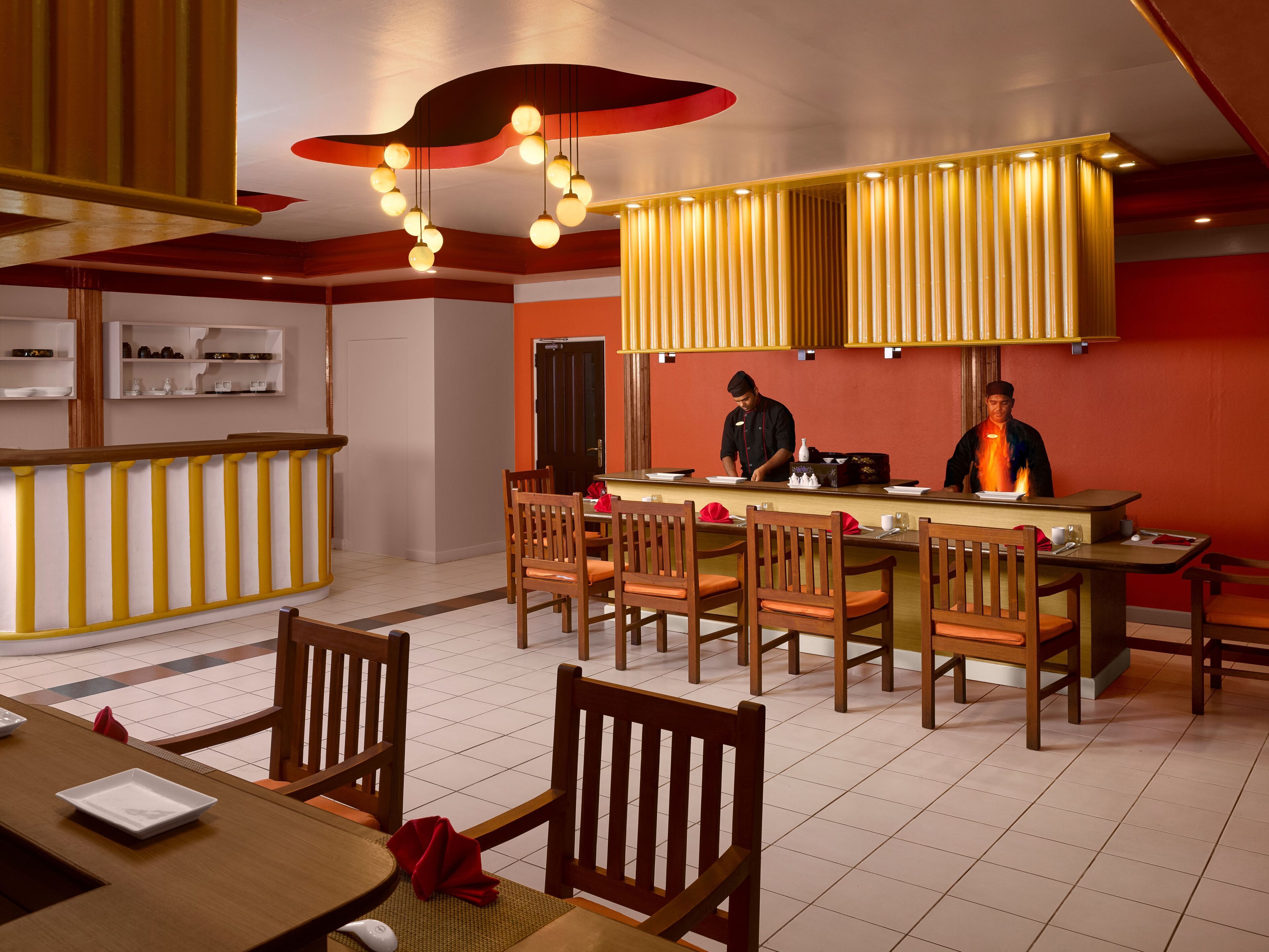 A restaurant with a bar area, wooden chairs, and a chef preparing food.
