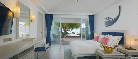 A hotel room with a bed, a desk, a chair, a TV, a ceiling fan, and a view of the outdoors.