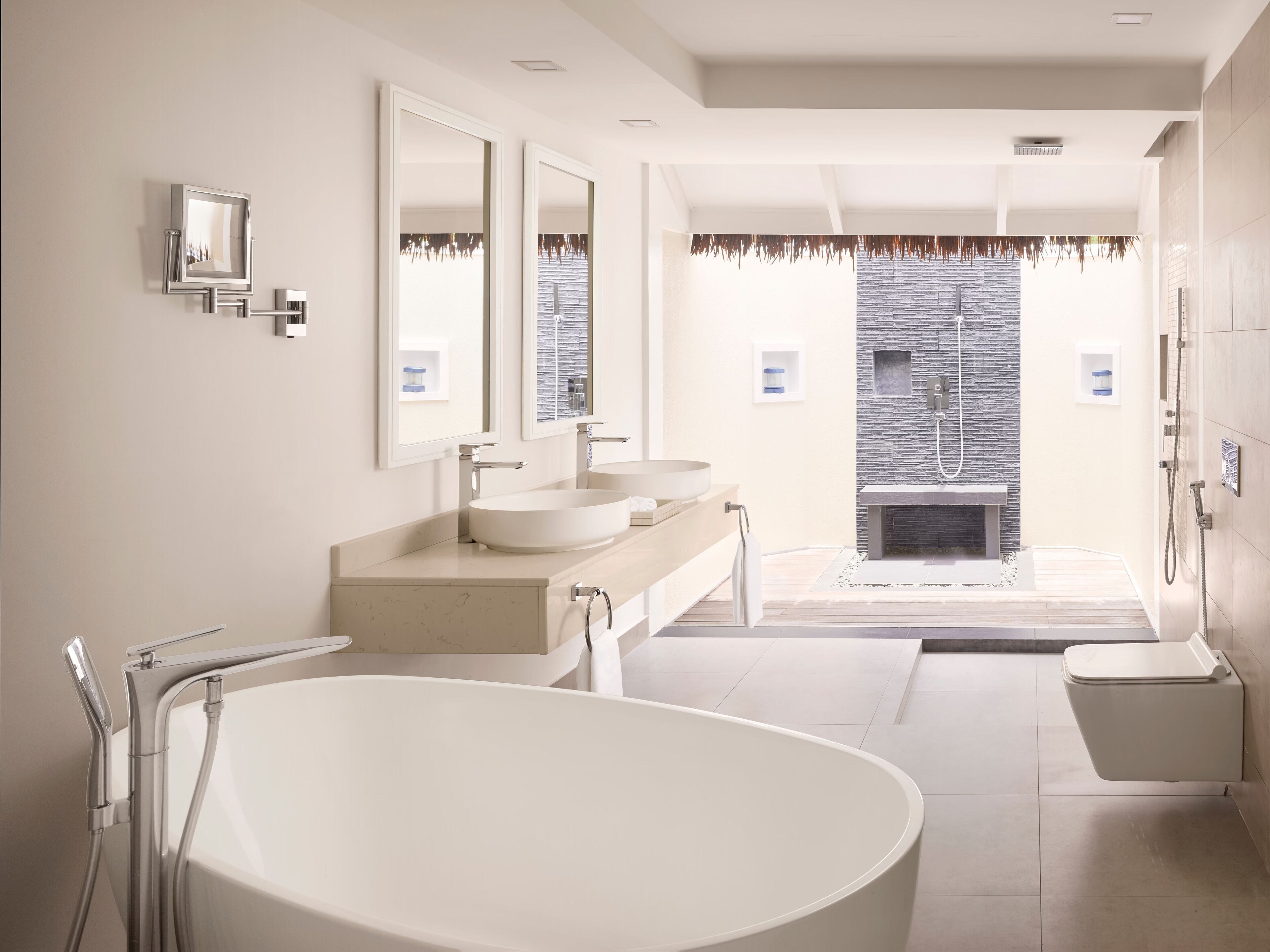 Ein modernes Badezimmer mit freistehender Badewanne, zwei Waschbecken und einer Duschkabine.