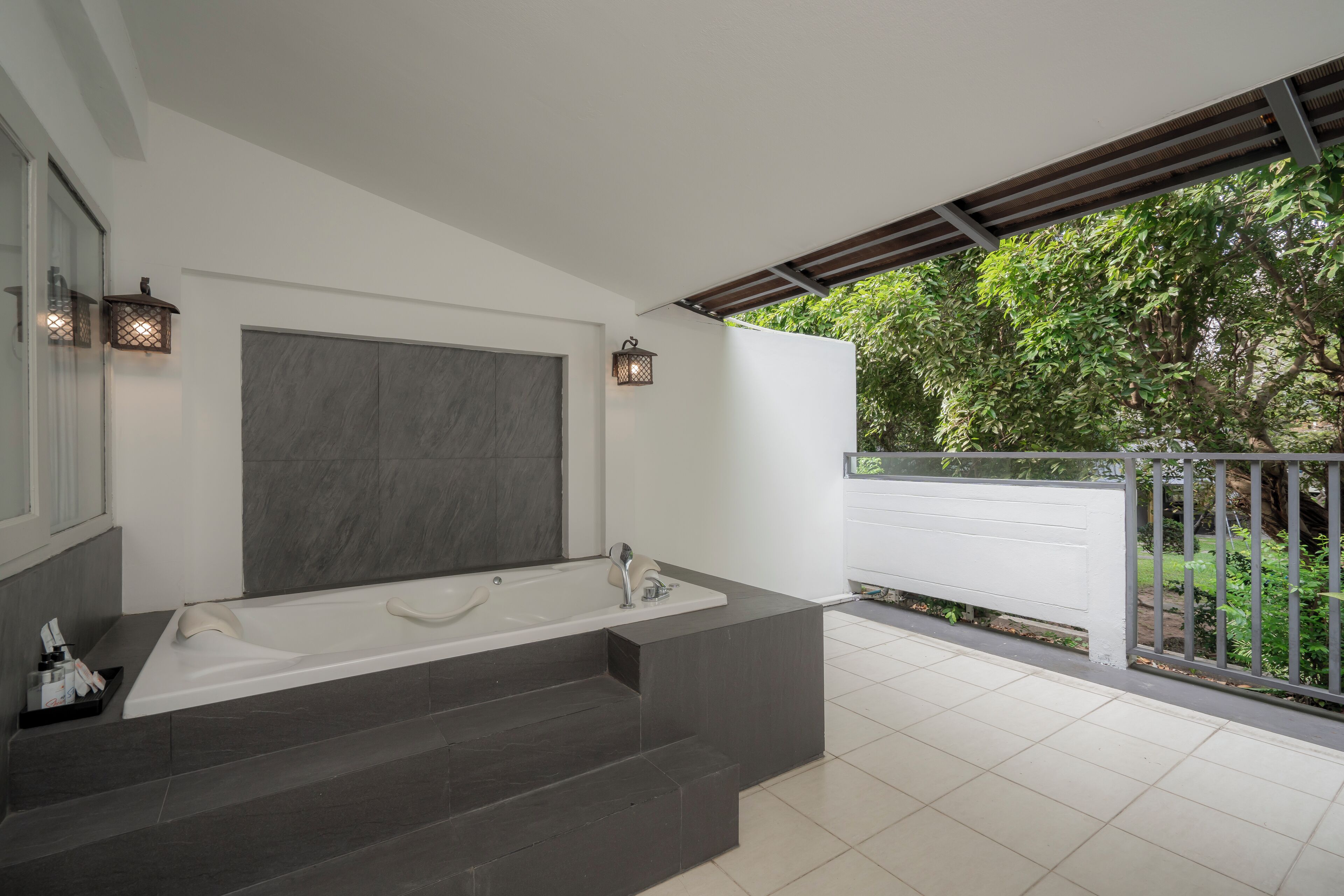A modern bathroom with a large bathtub, a mirror, and two wall-mounted lights.