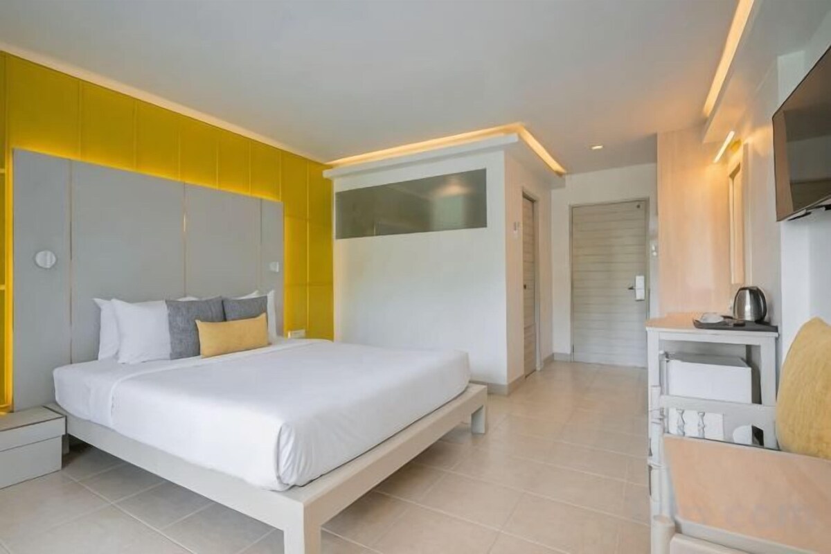 A modern hotel room with a large bed, bedside tables, a desk, and a television.