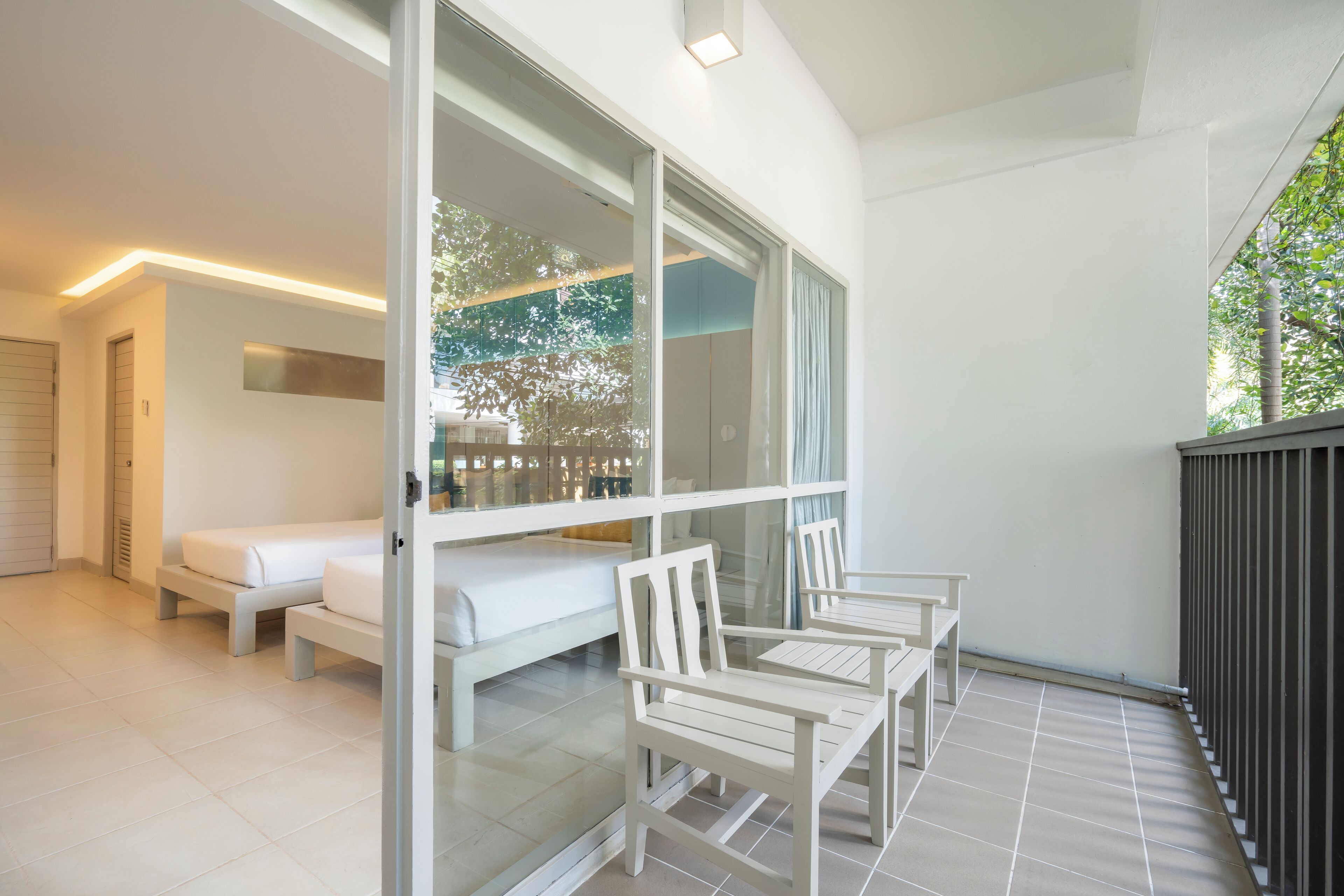 Quarto de hotel moderno com varanda, sofá e mesa de jantar.