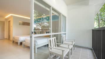 A modern hotel room with a balcony, a sofa, and a dining table.