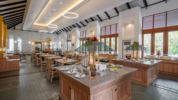 Een moderne eetruimte met meerdere tafels en een centraal buffet.