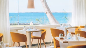A restaurant with a view of the ocean, featuring yellow chairs and white tablecloths. - Iberostar Selection Lanzarote Park (Yaiza)