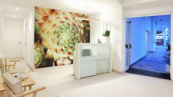 A reception area with a modern design, including a reception desk, seating area, and a large wall mural.