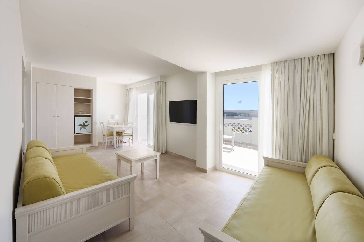 Una habitación amplia con una cama, un escritorio y un televisor.