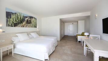 Un dormitorio con una cama grande, un escritorio y una silla. Hay un cuadro en la pared y una puerta que da a otra habitación.
